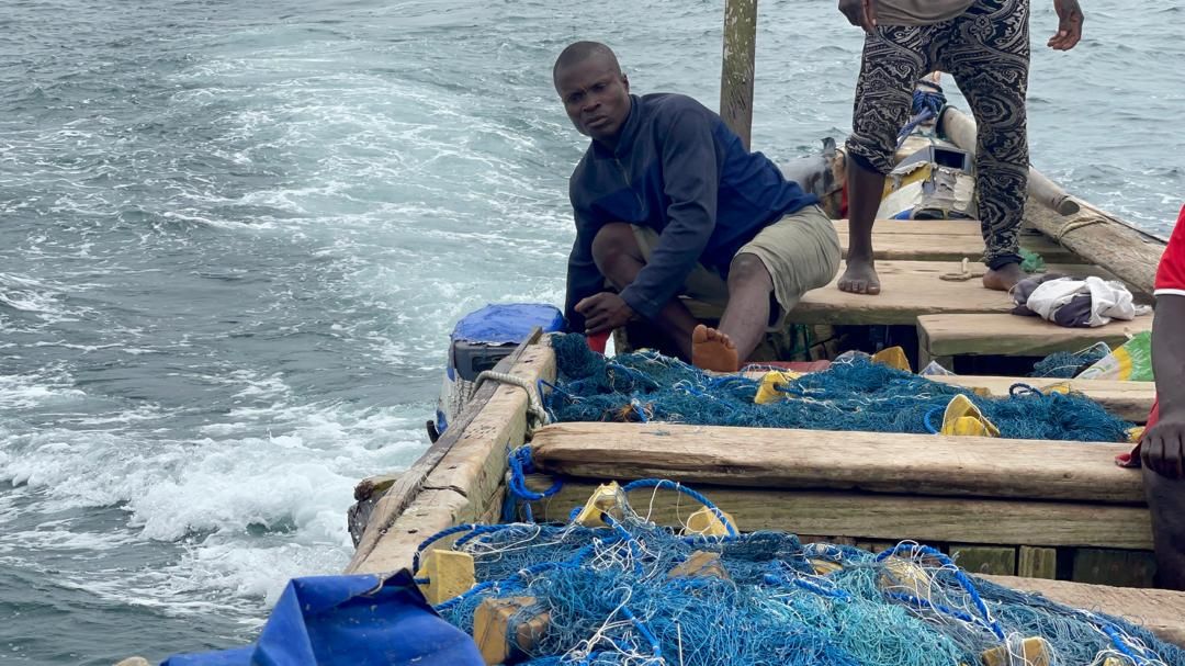 A fisherman aboard a canoe hauling in nets during the crew's day at sea