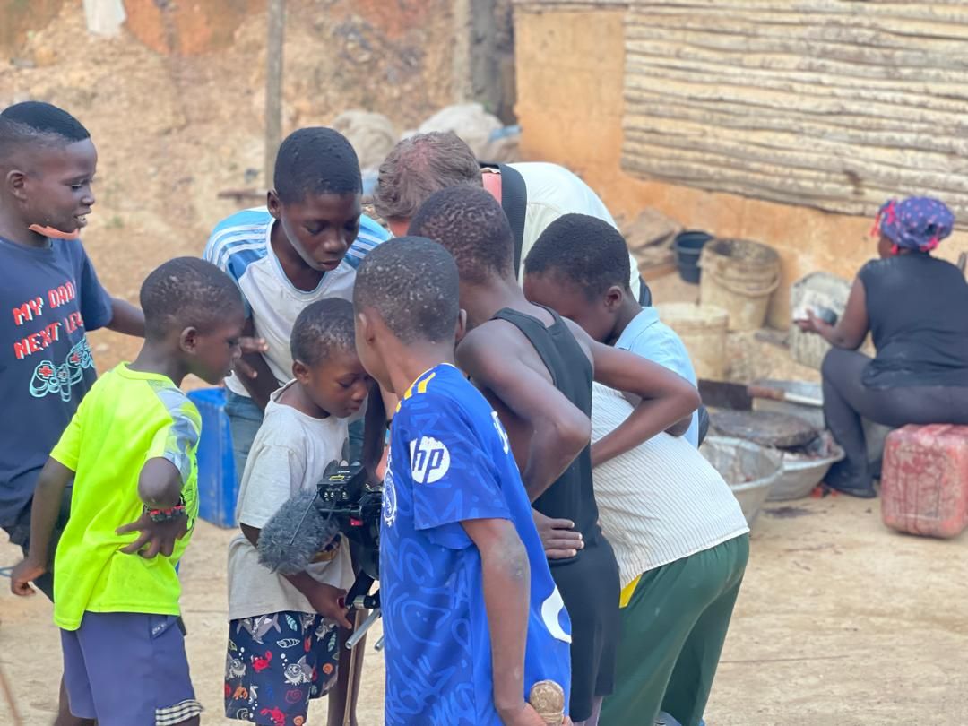 Local children gathering around the camera equipment on set in Dixcove
