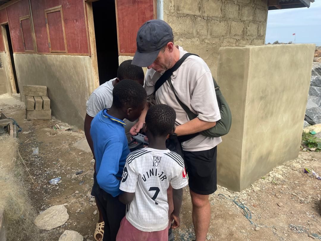 Crew sharing behind-the-scenes footage with local children in Dixcove