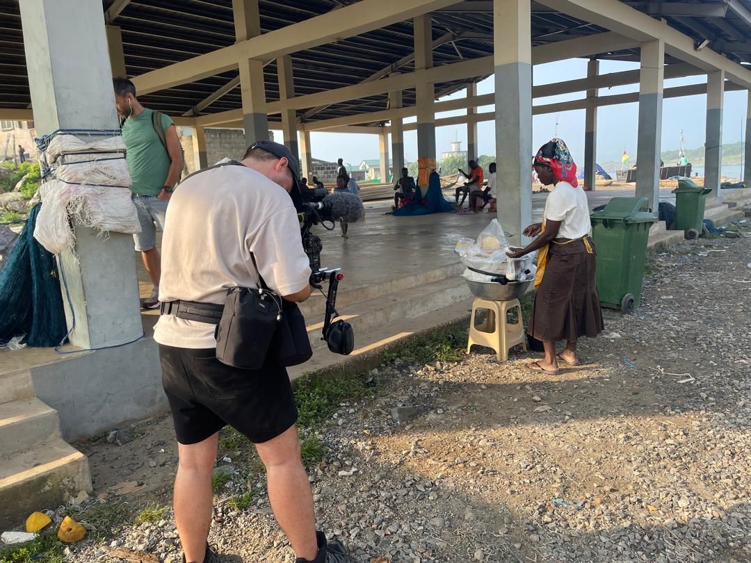 Crew filming a fish trader at the community market shelter in Dixcove