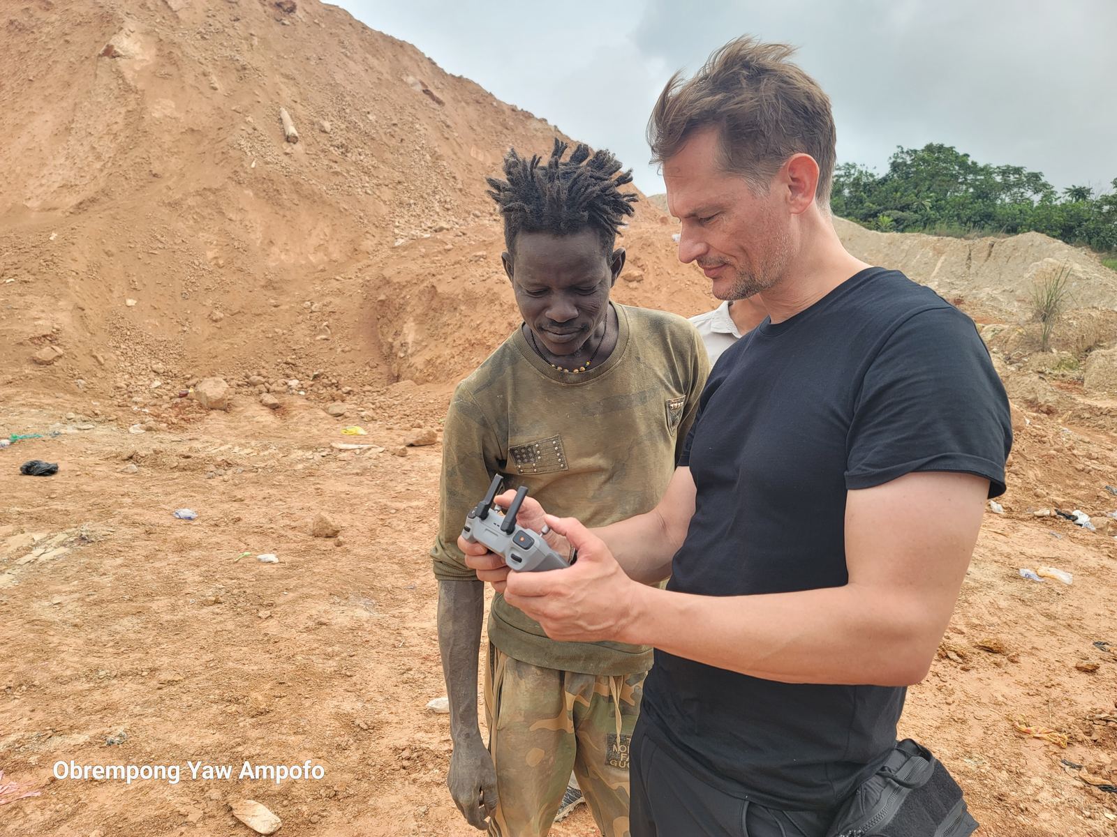 Crew member showing a young small-scale miner footage on a drone controller