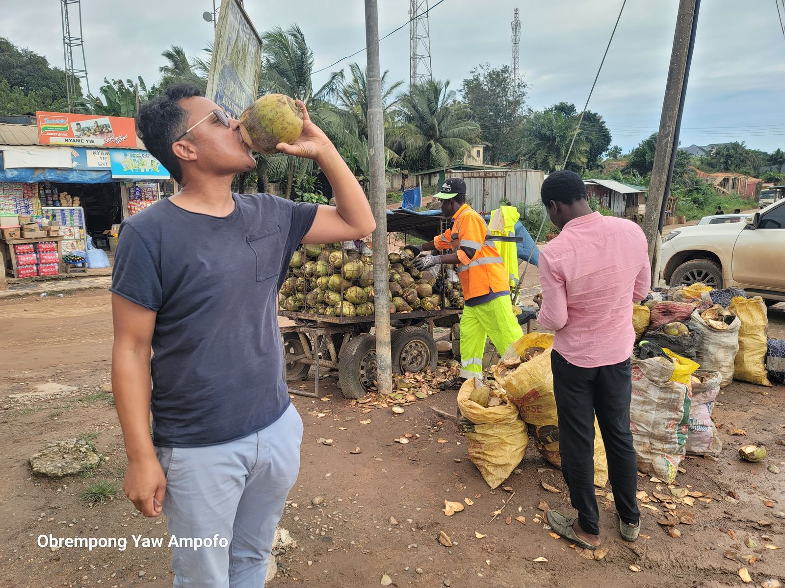 Crew member drinking fresh coconut water at a roadside stall