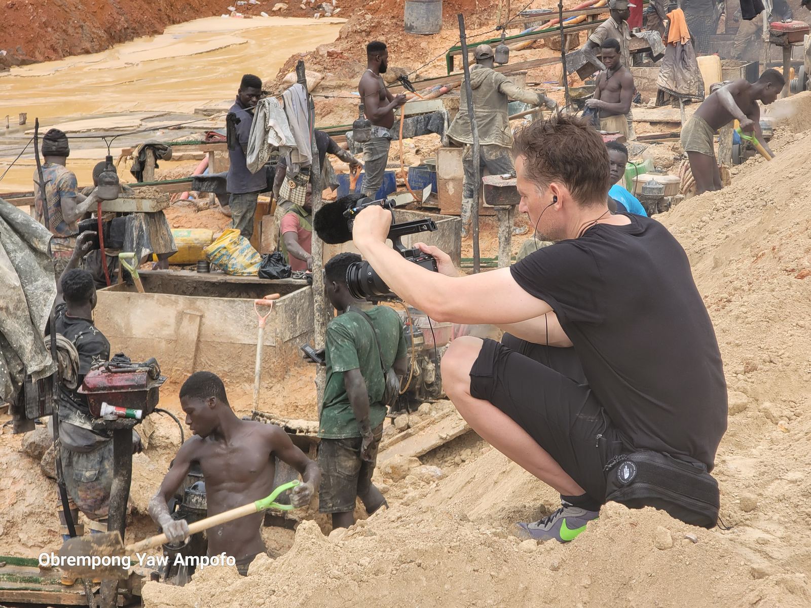 Cameraman filming small-scale miners washing ore at a mining site